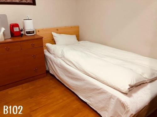 a bedroom with a white bed and a dresser at 冠京ホテル in Tokyo