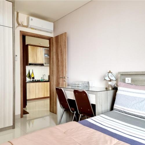 a bedroom with a bed and a desk and a kitchen at Apt Pejaten Park 1 BR Wood with Pool, Netflix & Washing Machine in Jakarta