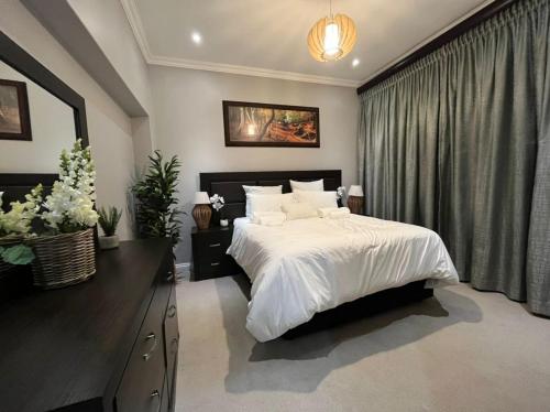 a bedroom with a large white bed and a window at Kiwi Boutique Lodges in Pretoria