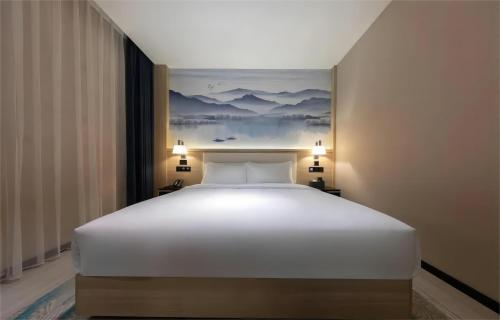 a large white bed in a room with a painting at Ausotel by Argyle Baiyun International Airport Renhe Metro Exit B in Guangzhou
