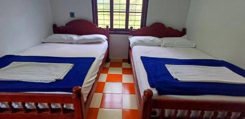 two twin beds in a room with a window at Wayanad Empire Villa in Kalpetta