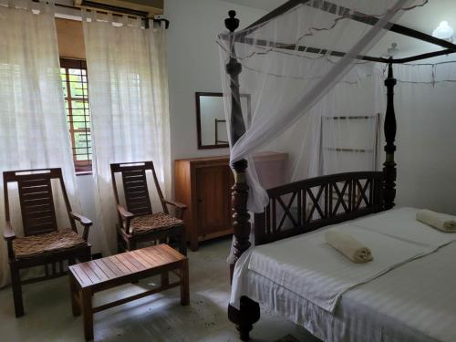 1 Schlafzimmer mit einem Himmelbett und 2 Stühlen in der Unterkunft Villa sea spray in Hikkaduwa