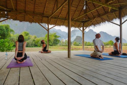 um grupo de pessoas sentadas em uma aula de yoga em Silver Naga Hotel em Vang Vieng