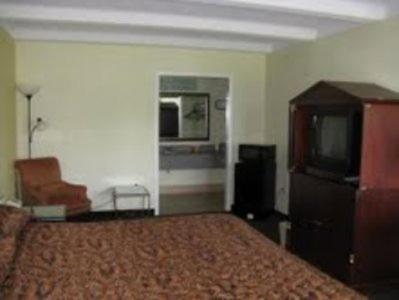 Habitación de hotel con cama y TV en Walking Horse Lodge, en Lewisburg