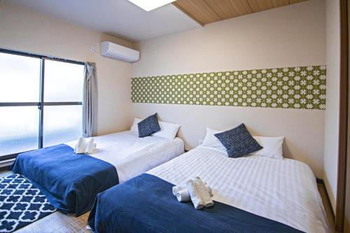 two beds in a room with a window at 福 源 閣 in Osaka