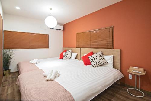 two beds in a bedroom with orange walls at - Miyu本庄西 - 2LDK 2ベッド2畳 梅田商店街まで徒歩圏内 隣有料駐車場 in Osaka