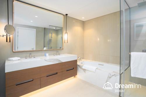a bathroom with a sink and a tub and a mirror at Dream Inn - Address Beach Residence - Free Beach Access in Fujairah