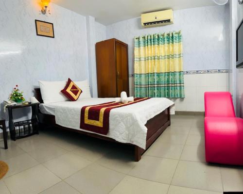 ein Schlafzimmer mit einem Bett und einem roten Stuhl in der Unterkunft Thiên Phước Hotel in Ho-Chi-Minh-Stadt