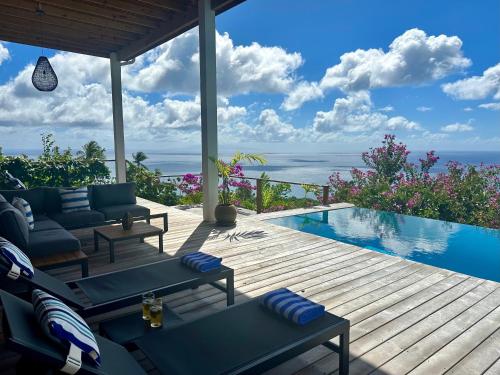 a wooden deck with a swimming pool next to a house at Infinity Luxury Villa - Stunning Sea and Piton Views in Soufrière