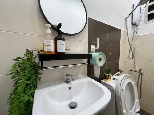 a bathroom with a sink and a mirror and a toilet at DeMUJI 4BR 10PAX 3Min to ECM KCM, PS4 in Kuantan