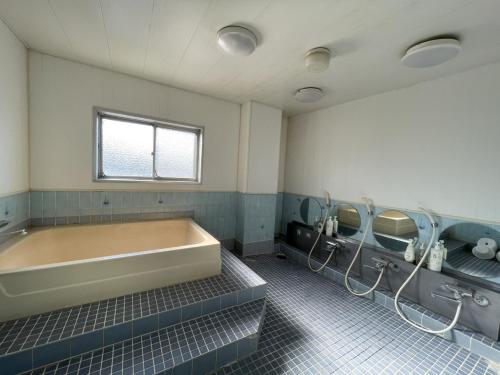 a bathroom with a large tub and two mirrors at Zentsuji Grand Hotel in Zentsuji