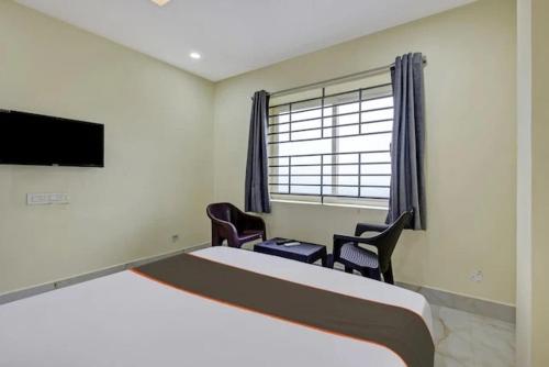 a bedroom with a bed and two chairs and a tv at Ns Beach Resort in Bhīmunipatnam