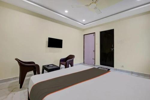 a bedroom with a bed and two chairs and a tv at Ns Beach Resort in Bhīmunipatnam