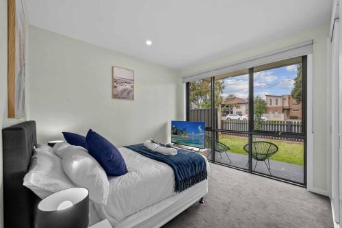 a bedroom with a bed and a balcony with a television at Churchill Delux, close to Western health 10 min to Cbd in Braybrook