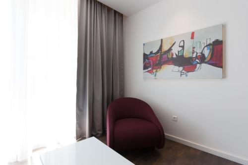 a room with a red chair and a painting on the wall at Perla Luxury in Ulcinj