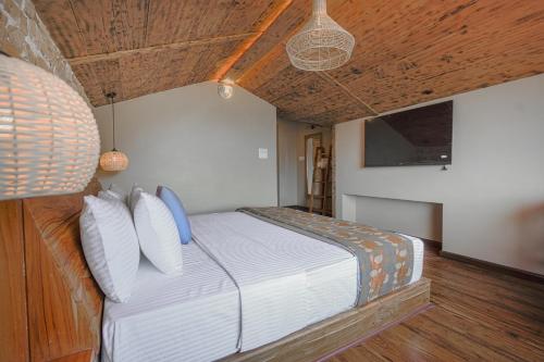 a bedroom with a bed with white sheets and blue pillows at Saanjh - The Musical Sunset in Shimla