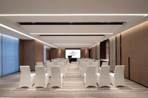 a conference room with white chairs and a screen at Crowne Plaza Jinan Runhua by IHG in Jinan