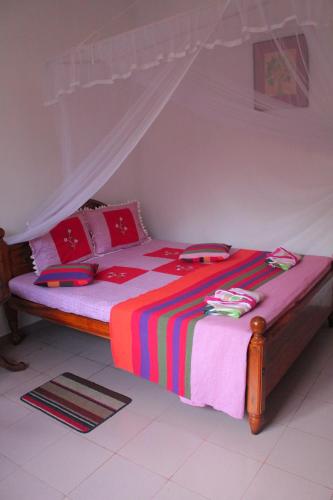 un letto con coperte e cuscini colorati in una stanza di Mango House a Talalla South