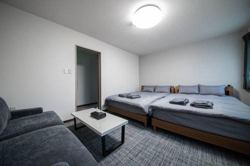 a hotel room with two beds and a couch at THE NORTH PEAK 202 in Furano