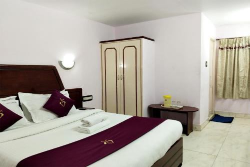 a bedroom with a large bed with purple and white pillows at Hotel Mount View in Kodaikānāl