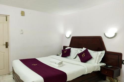 1 dormitorio con 1 cama grande con almohadas moradas y blancas en Hotel Mount View, en Kodaikanal