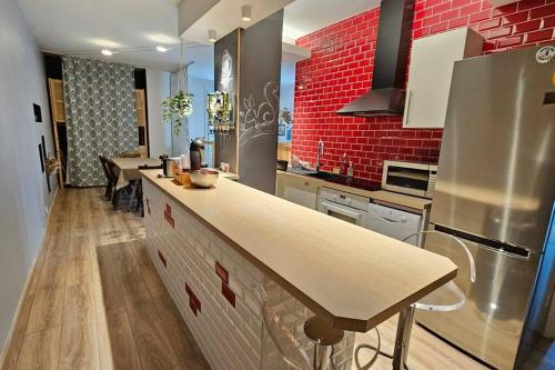 une cuisine avec un comptoir et un mur en briques rouges dans l'établissement Le Royat Palace - Wifi - Confort, à Royat
