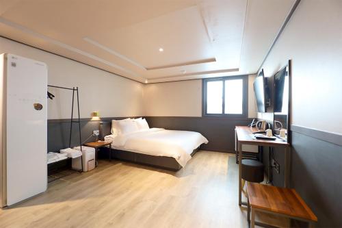 a bedroom with a bed and a desk and a television at Hotel Mar Samsan in Ulsan