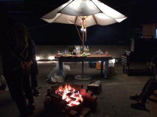 a table with a fire in front of a table with an umbrella at 絶景シーサイドナハマ-BBQとサウナ-海まで徒歩60秒w in Yokosuka