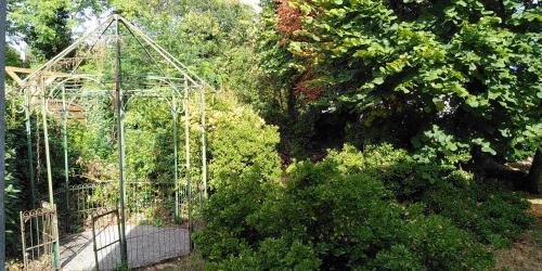 ein Metall-Gewächshaus in einem Garten mit Bäumen in der Unterkunft Villa Lulu in Mérignac