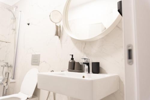 La salle de bains blanche est pourvue d'un lavabo et d'un miroir. dans l'établissement Luxury Brand New Win Herastrau, à Bucarest