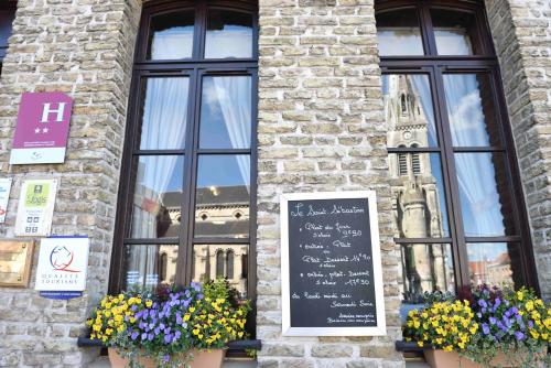 a building with two windows with flowers and a chalkboard at Le Saint Sébastien in Blendecques