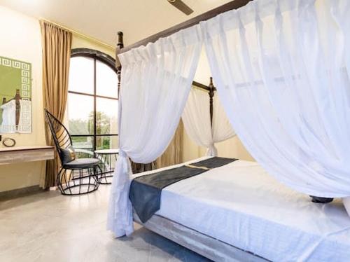 1 dormitorio con 1 cama con cortinas y silla en Skilight Villa en Indore
