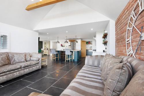 a living room with two couches and a brick wall at Priory Farm Cottage in Colchester