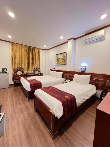 a hotel room with two beds and a desk at Hanoi Asia 2 Long Bien in Hanoi