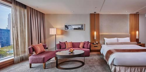 a large hotel room with a bed and a couch at Millennium Hotel Taichung in Taichung