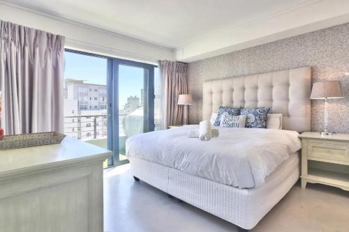 1 dormitorio con 1 cama blanca grande y ventana grande en Stylish sea-facing apartment with underground parking, en Ciudad del Cabo