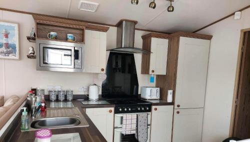 a small kitchen with a stove and a sink at 149 Holiday Resort Unity 6 berth Passes optional No pets in Brean