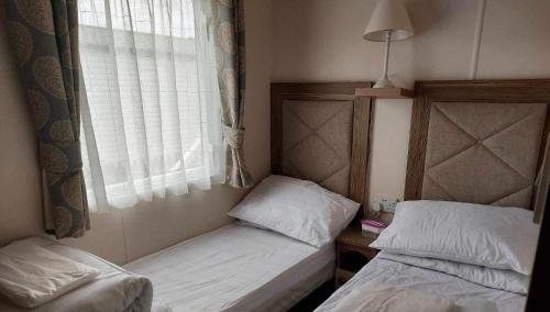 Duas camas num pequeno quarto com uma janela em 149 Holiday Resort Unity 3 bed Entertainment passes included em Brean