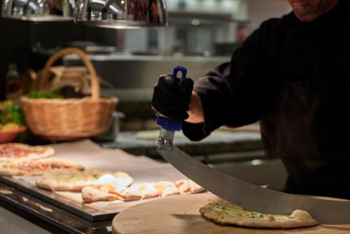 a person cutting a pizza with a knife at Esperos Mare Resort & Spa in Faliraki