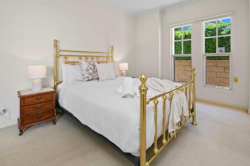 a bedroom with a gold bed with a night stand and a window at Beaumont Bliss: 4BR 2 5BA Family Retreat in Glenunga