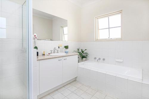 a white bathroom with a tub and a sink at Beaumont Bliss: 4BR 2 5BA Family Retreat in Glenunga