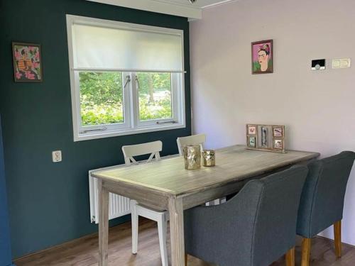 a dining room table with chairs and a window at Spacious Chalet in Garderen with Fenced Garden in Garderen