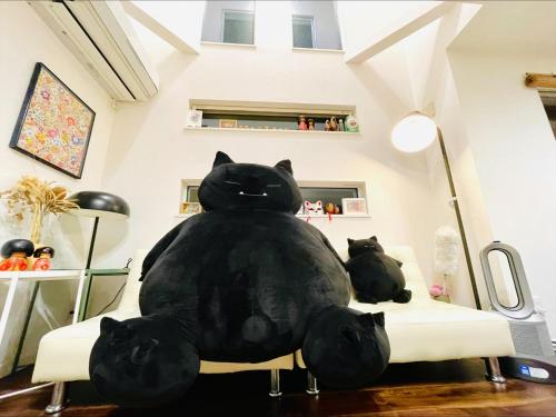 a large black cat sitting on a couch in a room at Tanuki Shinjuku in Tokyo