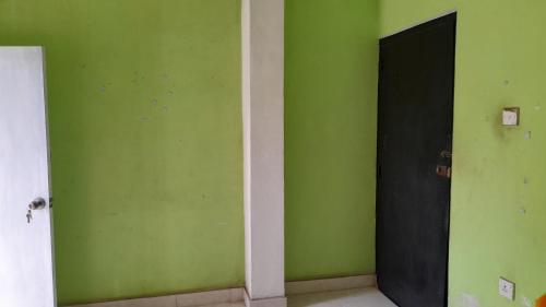 um quarto vazio com paredes verdes e uma porta preta em Kandy Forigners Home Stay em Katugastota