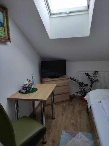 a attic room with a table and a television at Homestay Stróżówka in Gorlice