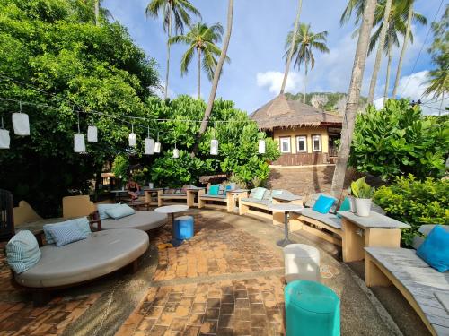 a patio with couches and tables and palm trees at Vacation Village Phra Nang Inn - SHA Extra Plus in Ao Nang Beach