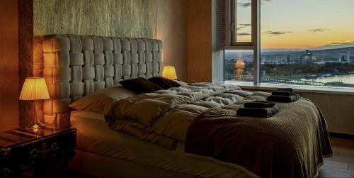 a bedroom with a large bed with a large window at Magna Vita apartment in Bratislava