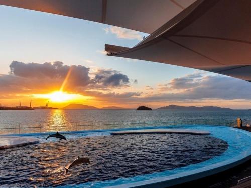 a swimming pool with a sunset in the water at Zentsuji Grand Hotel in Zentsuji