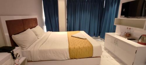a bedroom with a large bed with blue curtains at Grand Dyad Hotel - Near Kokilaben Hospital Andheri West in Mumbai
