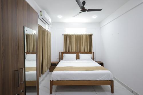 een slaapkamer met 2 bedden en een plafondventilator bij INDIGO PALMS in Trivandrum